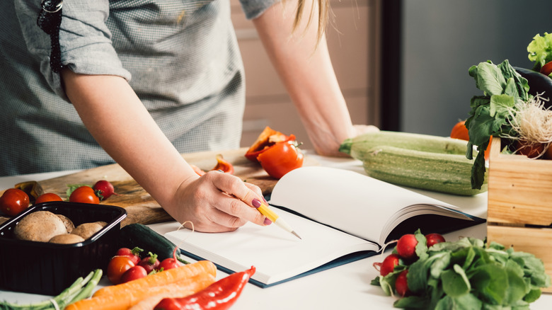 Cook leaning over cookbook notes 