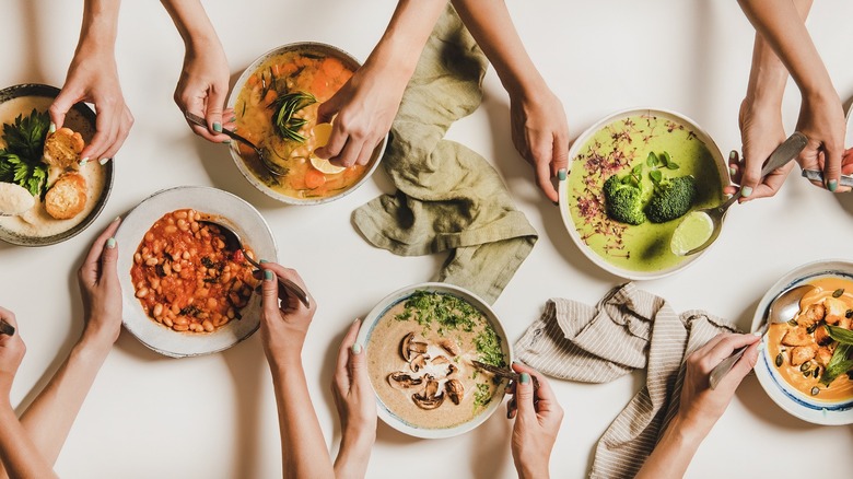 People holding many soup bowls