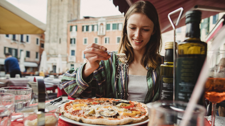 sprinkling cheese on pizza