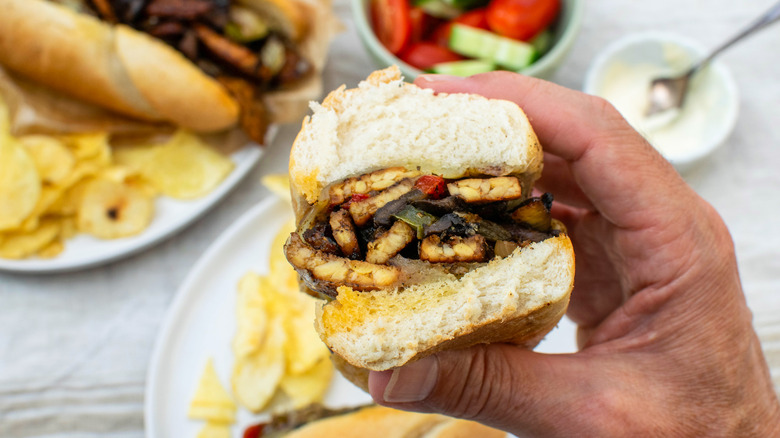 person holding Tempeh Cheesesteak sandwich