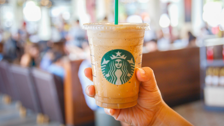 holding starbucks drink in cafe