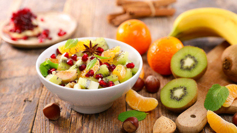 Fruit salad in white bowl with oranges, kiwis, pomegranate seeds