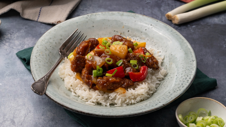 sweet and sour pineapple pork over rice on plate