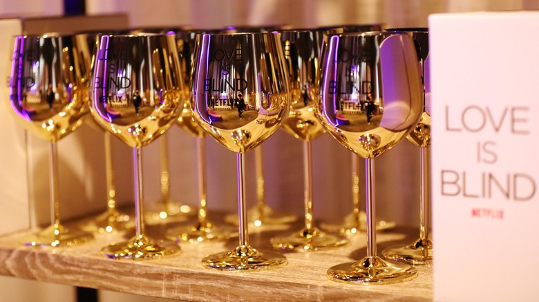 Several "Love Is Blind" branded gold wine glasses 