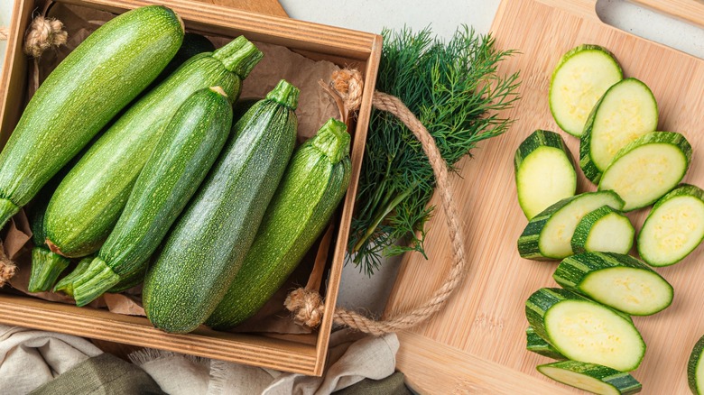 Top-down view of several whole zucchinis next to sliced zucchinis