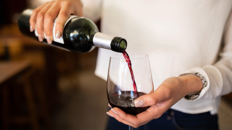 person pouring wine into glass