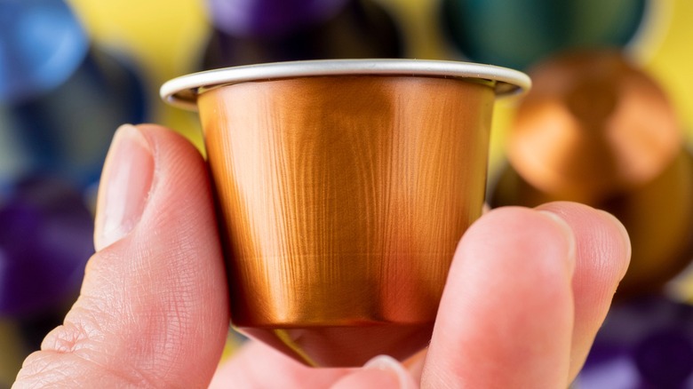 Fingers holding a Nespresso capsule