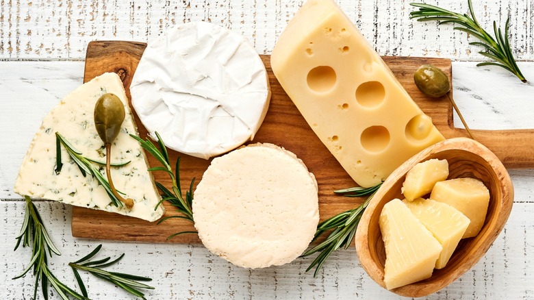 Top-down view of various cheeses on a wooden board