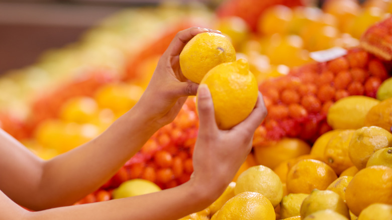 Hands comparing lemons in store