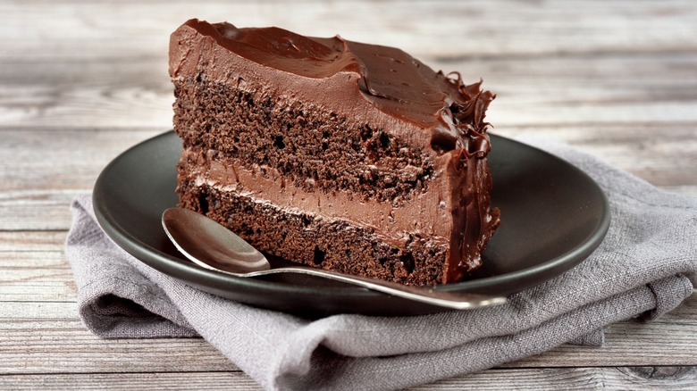 A slice of vegan chocolate cake on a plate with a spoon