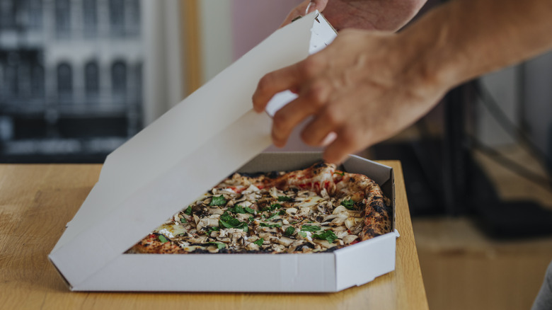 Person opening a pizza box from a convenience store