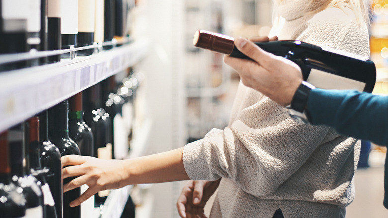 People reading a wine label in liquor store