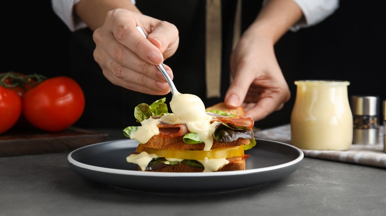 person spreading mayonnaise on sandwich