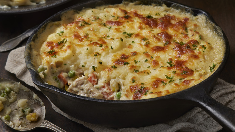 A chicken casserole in a cast iron pan next to a spoon