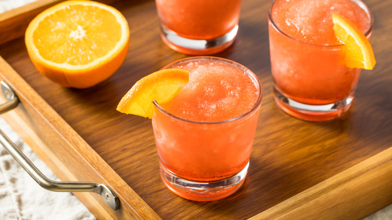 Orange whiskey frozen slushies garnished with orange wedges